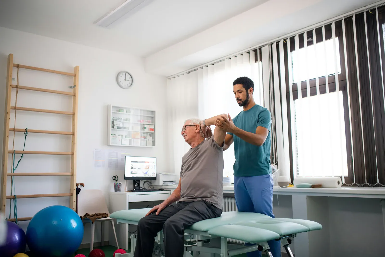A physical therapist helping a seated patient stretch his arm